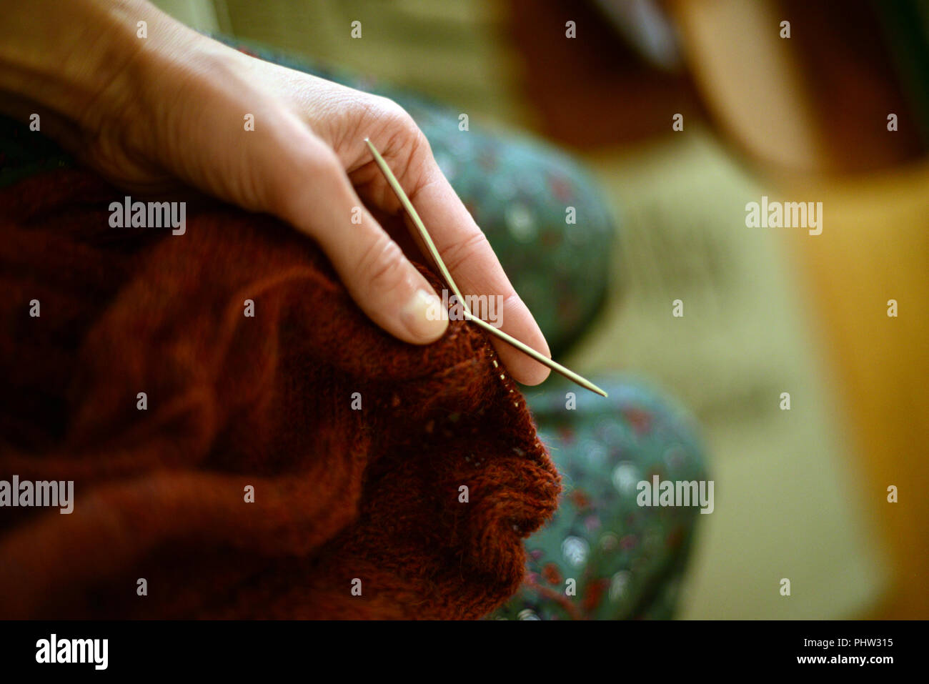 Donna che mantiene un degli aghi di tessitura con maglia in materiale lapideo in color rame Foto Stock