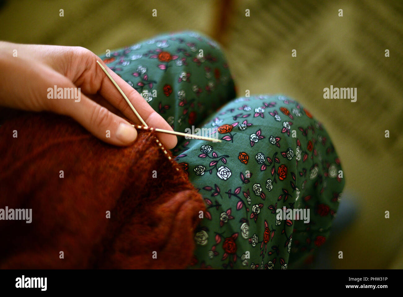 Donna che mantiene un degli aghi di tessitura con maglia in materiale lapideo in color rame Foto Stock