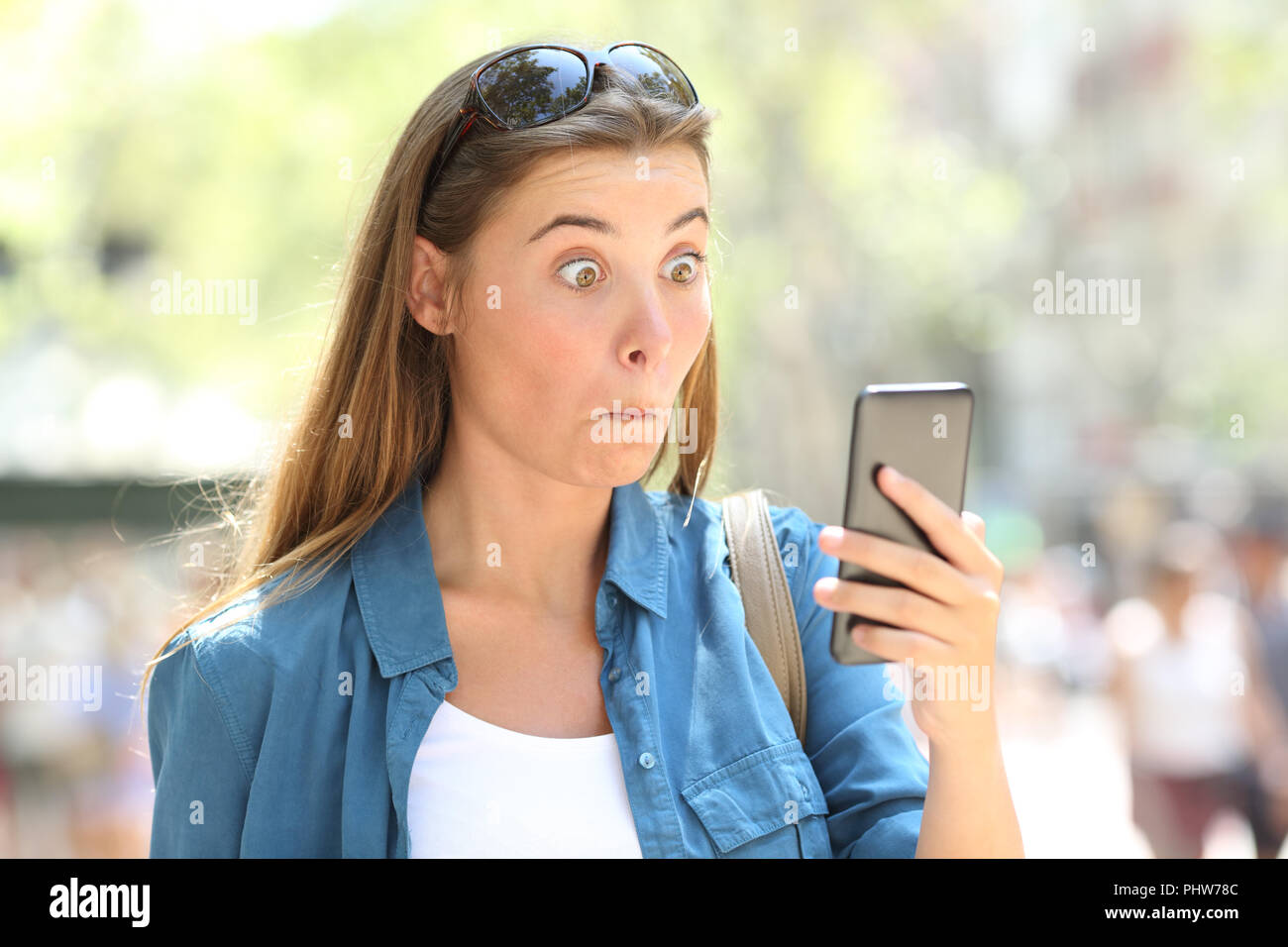 Ritratto di una donna stupito lettura smart phone contenuto in strada Foto Stock