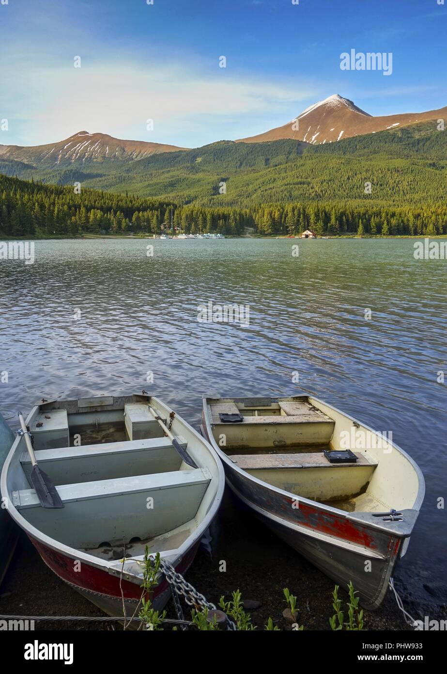 Canoe Barche sul Lago Maligne con distante Canadian Rocky Mountain cime del Parco Nazionale di Jasper all'orizzonte Foto Stock