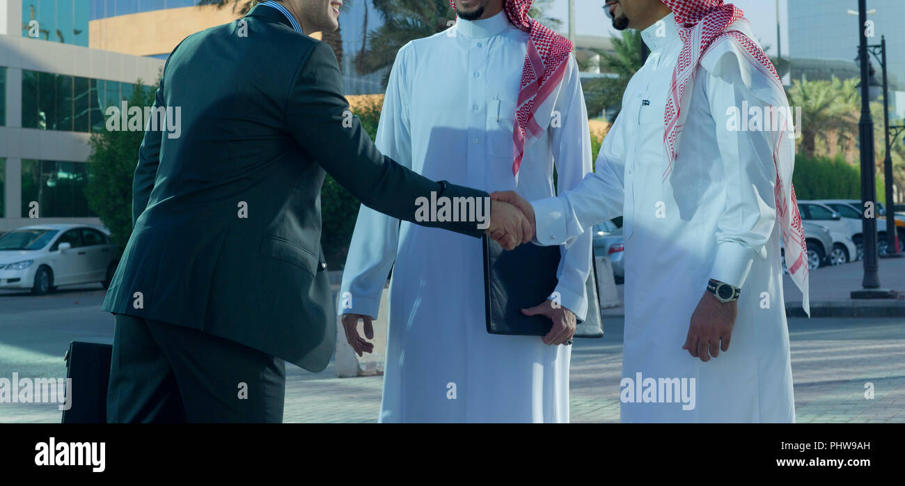 Medio Oriente e imprenditori caucasica stringono le mani all'aperto in una giornata di sole Foto Stock