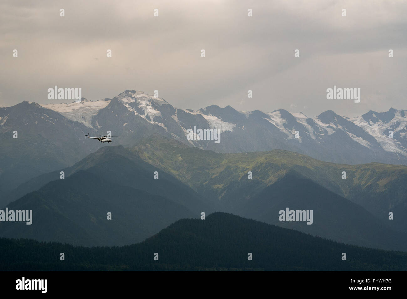 Un vecchio stile sovietico elicottero vola attraverso un paesaggio impressionante vista di Snow capped Caucaso gamme della montagna. Foto Stock