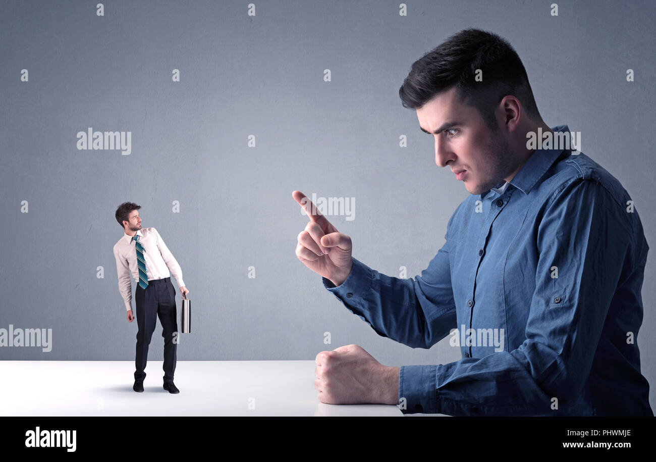 Giovane imprenditore professionale essendo arrabbiato con un altro imprenditore in miniatura Foto Stock