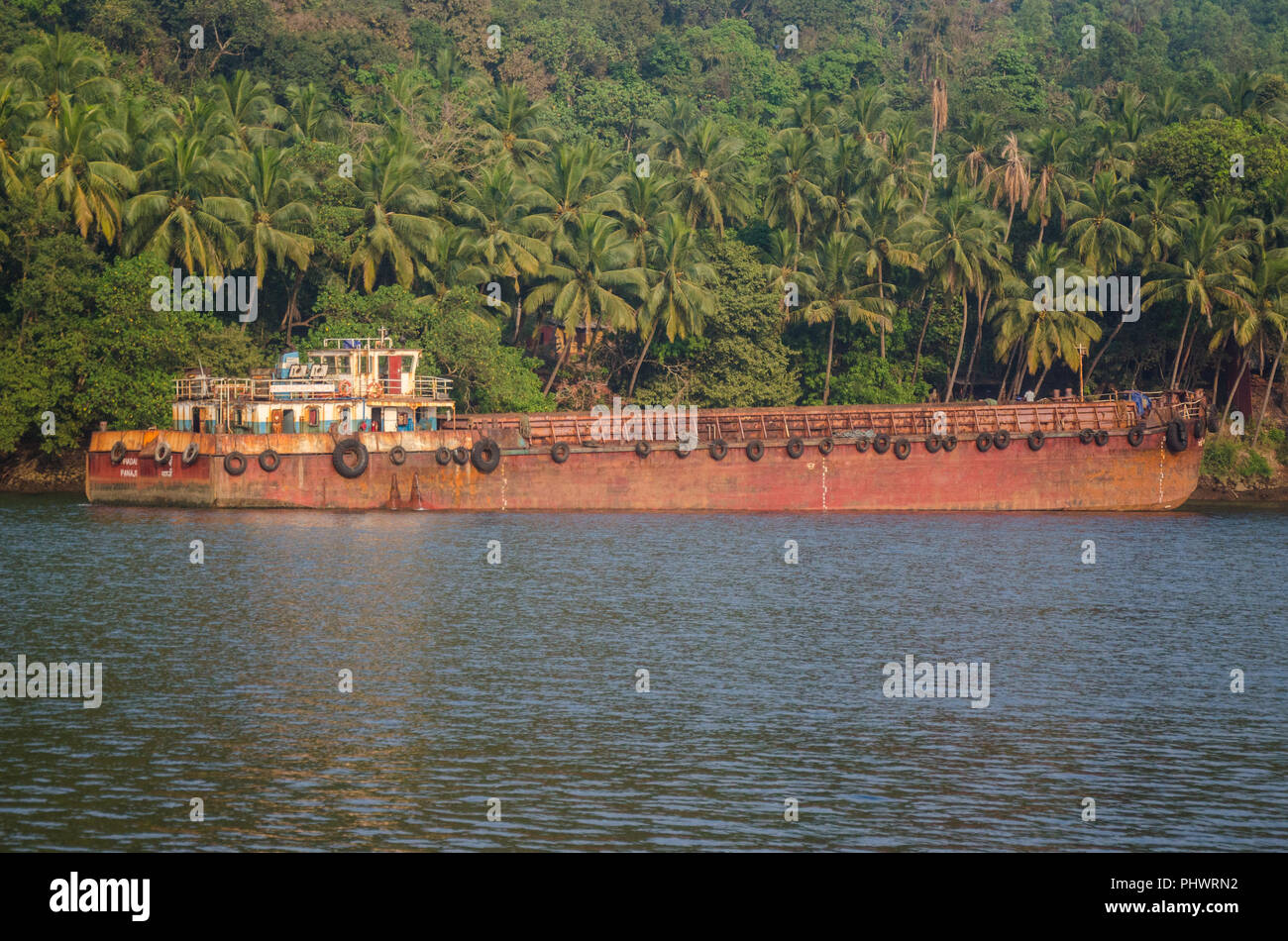 Un massiccio barge ancorato a riva in prossimità Volvoi Ferry Terminal, Savoi Verem; arrugginimento in pace dopo il divieto di data mining in Goa, India. Foto Stock