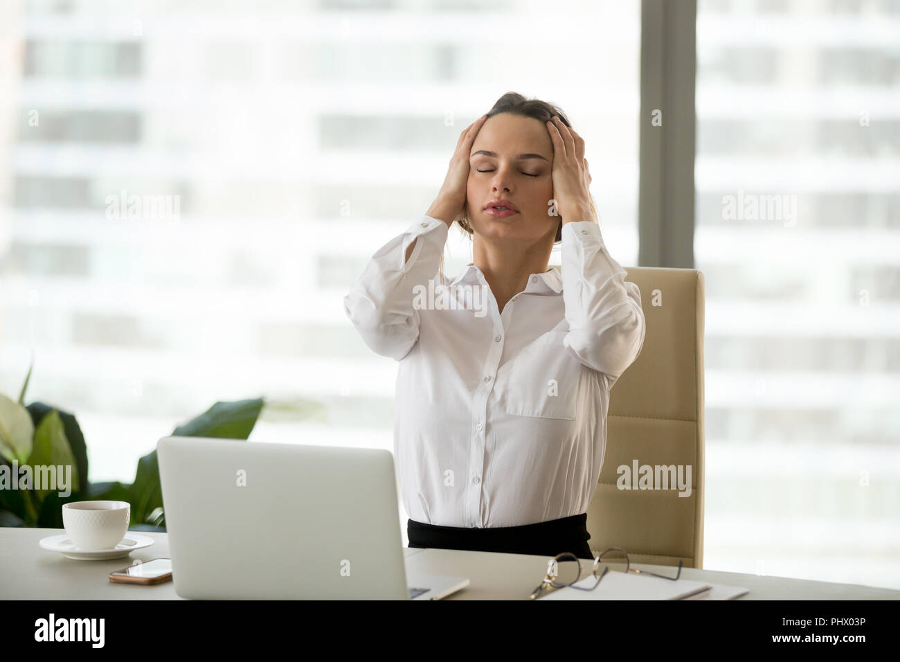 Sottolineato imprenditrice avente mal di testa al lavoro tenendo la testa in h Foto Stock