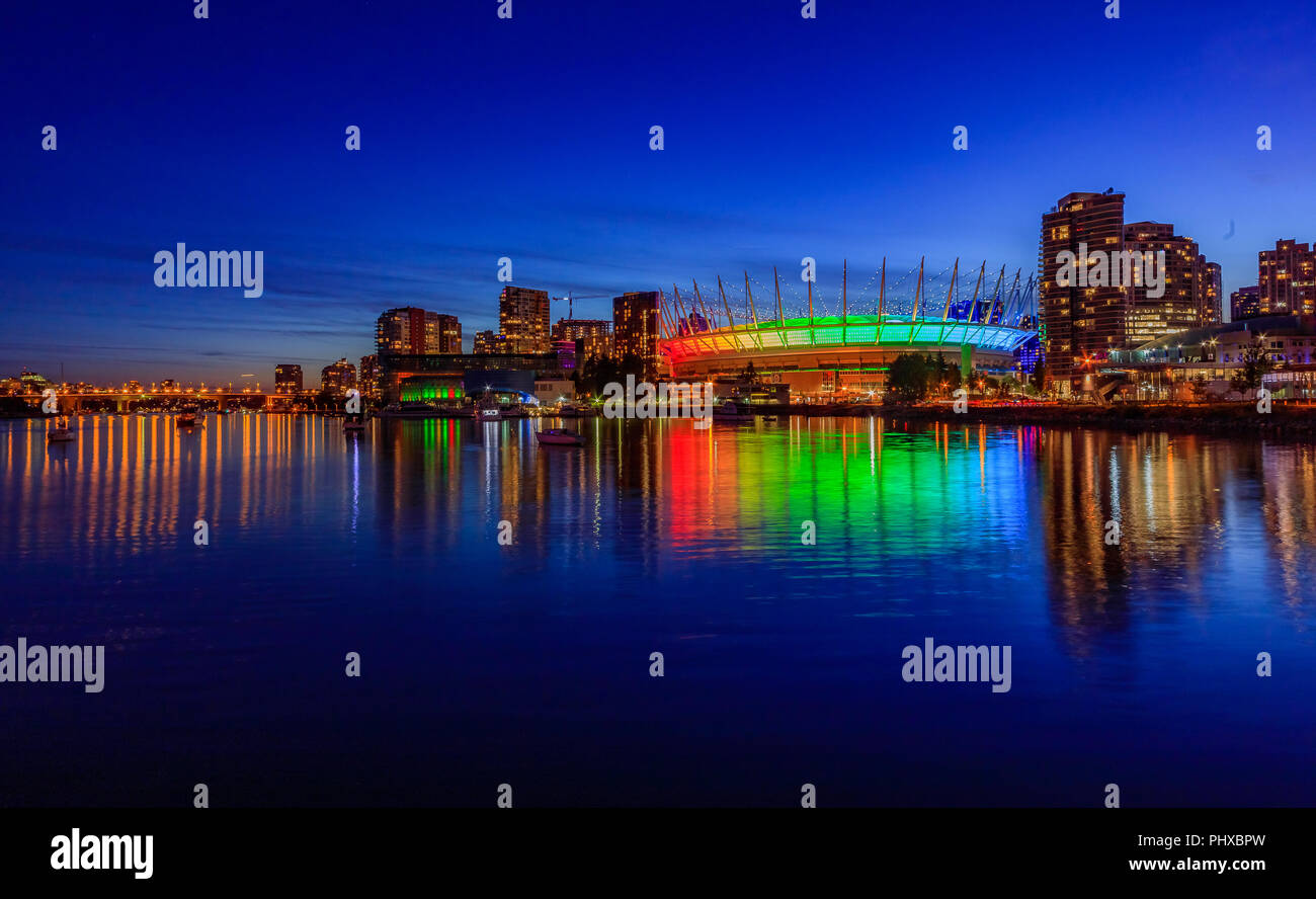 Lo skyline di Vancouver su False Creek e illuminato BC Place Stadium di notte in British Columbia, Canada Foto Stock