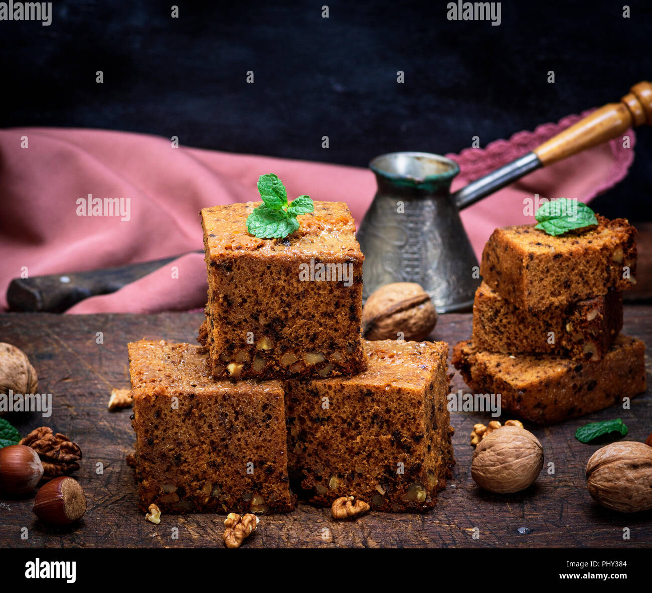 Pila di piazza al forno fette di torta con le noci su un marrone tavola di legno, un pan di spagna, close up Foto Stock