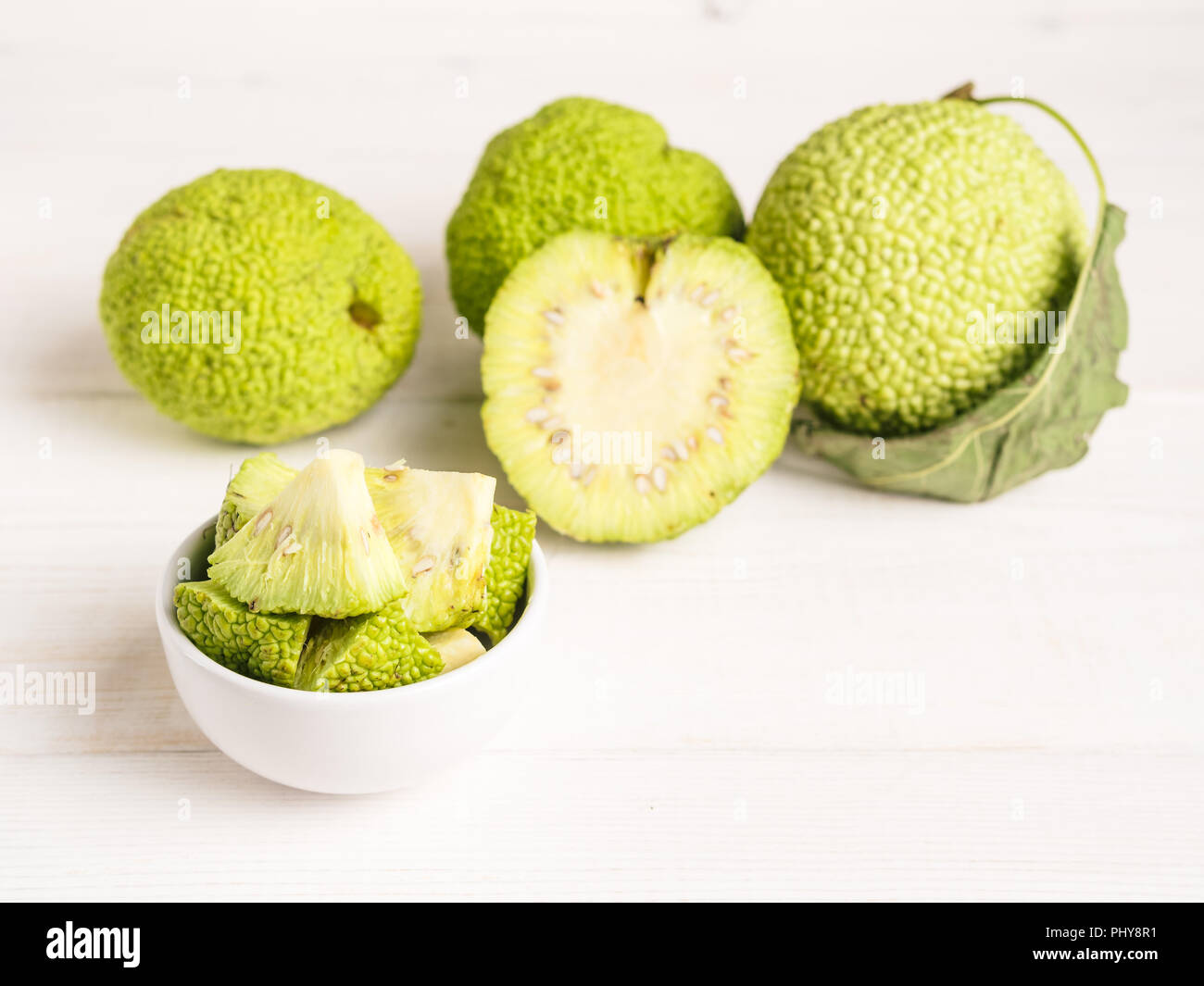 Frutta verde di maclura pomifera,osage orange,cavallo apple,adam Apple a crescere su bianco tavolo in legno. Maclura pezzi nella piastra pronta per la preparazione di unguento. Maclura uso nella medicina alternativa. Spazio di copia Foto Stock