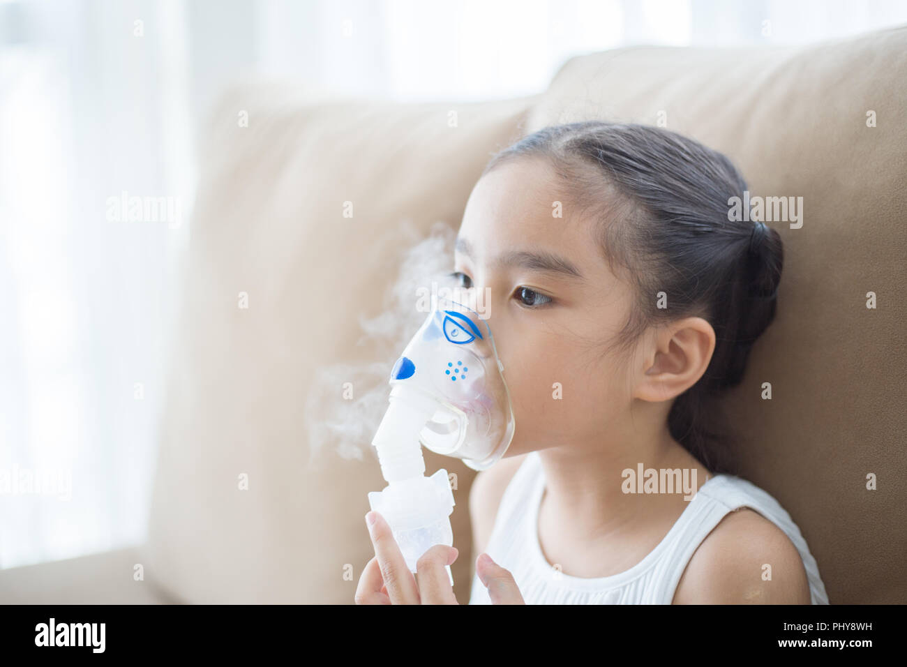 Carino bambino asiatico paziente terapia di inalazione dalla maschera di inalatore con flusso di morbida del fumo da broncodilatatore. Foto Stock