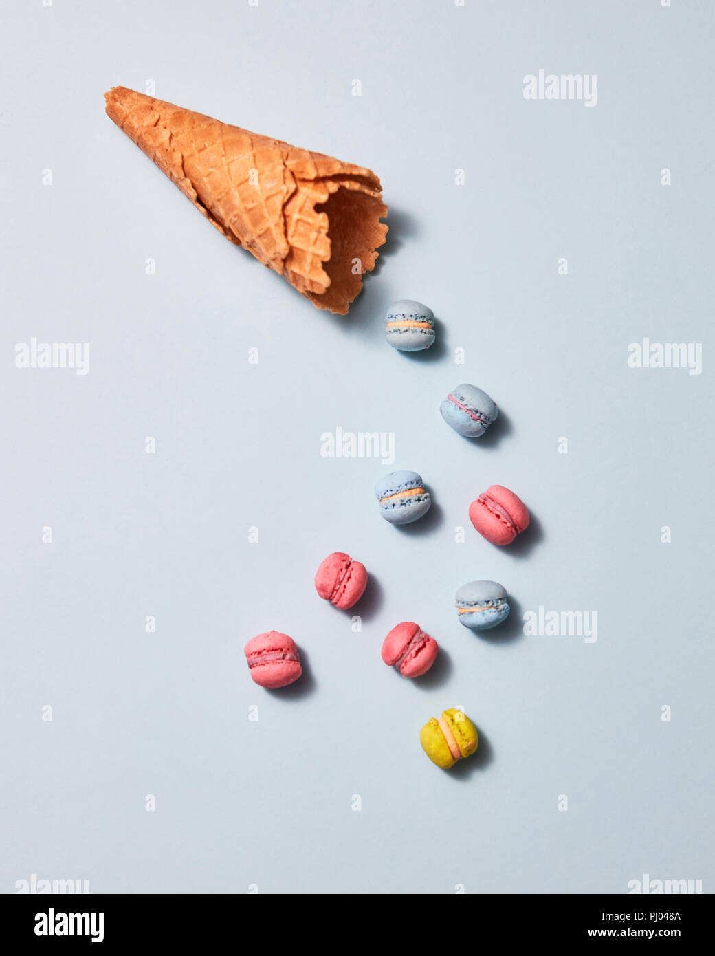 Amaretti multicolore e cono di cialda presentata su uno sfondo grigio. Lay piatto Foto Stock
