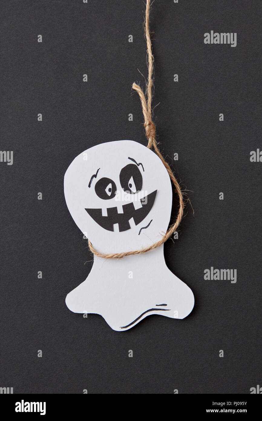 Halloween biglietto di auguri con ridere battenti scary Casper pendente da una corda fatti a mano da carta su un nero . Foto Stock