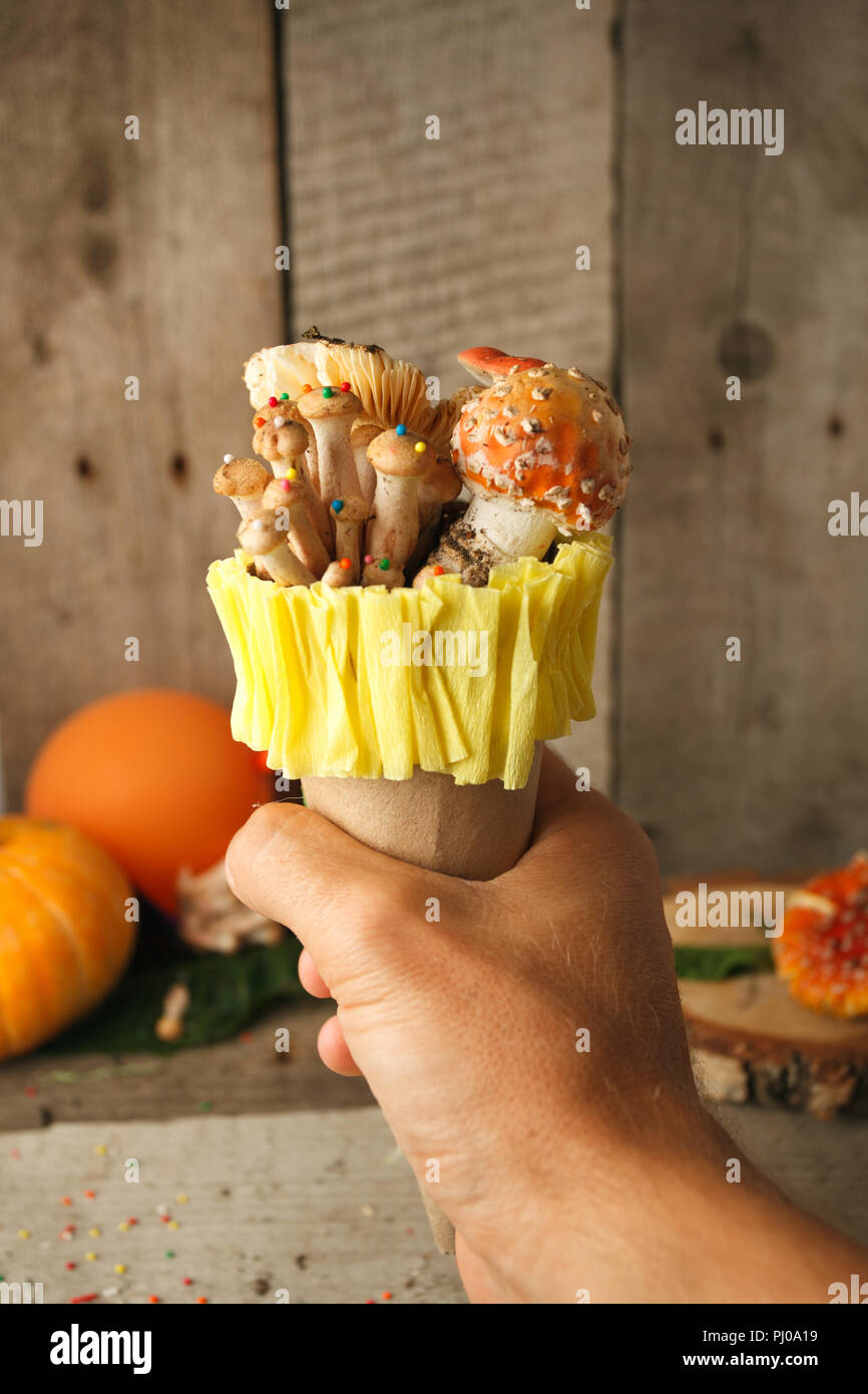 Fantastico gelato con la caramella mashroom in mano su sfondo di legno, concetto di poisin, nagic cibo, halloween vacanza divertente cibo Foto Stock