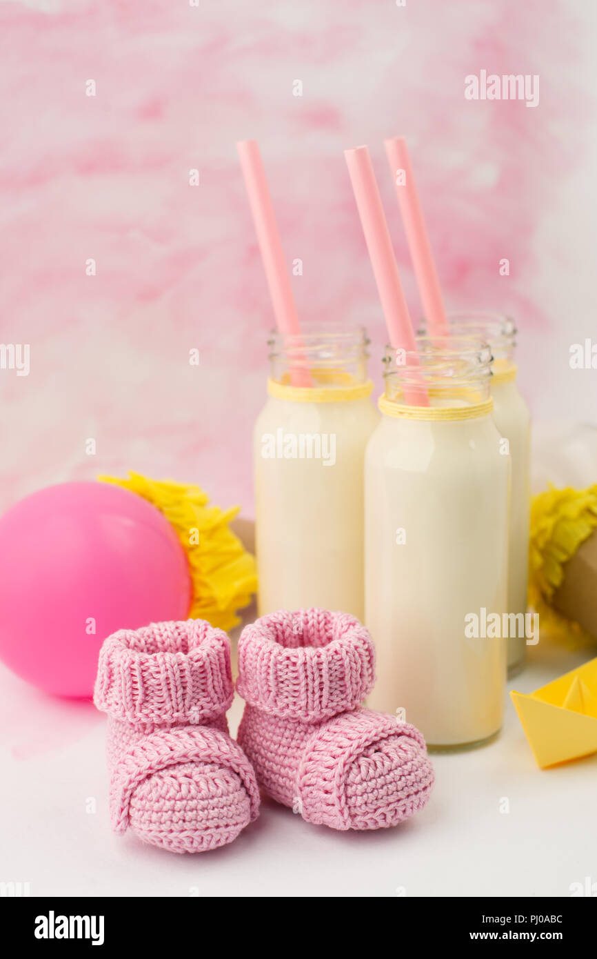 Baby doccia tavolo decorativo con spazio copia, rosa bambina stivaletti e bottiglie di latte in background color pastello, idea di bambino, doccia decor Foto Stock