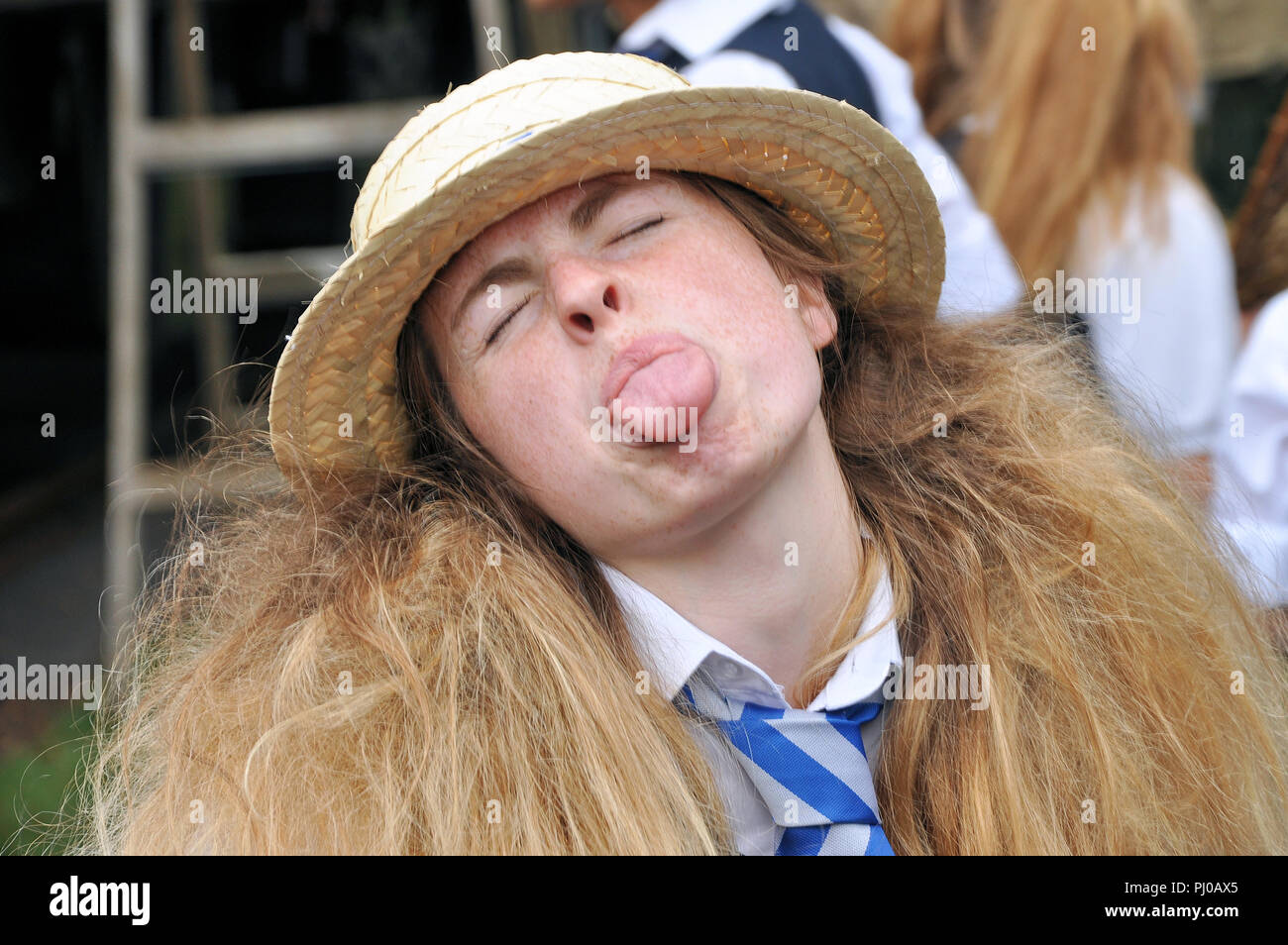 La ragazza di St Trinian e' cattiva al Goodwood Revival. Tirare fuori la lingua. Tirare una faccia. Soffia lampone Foto Stock