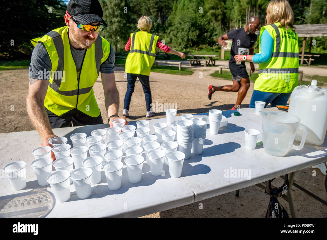 Bianco tazze di plastica riempito di acqua per essere consegnato al runner in una giornata calda. Foto Stock