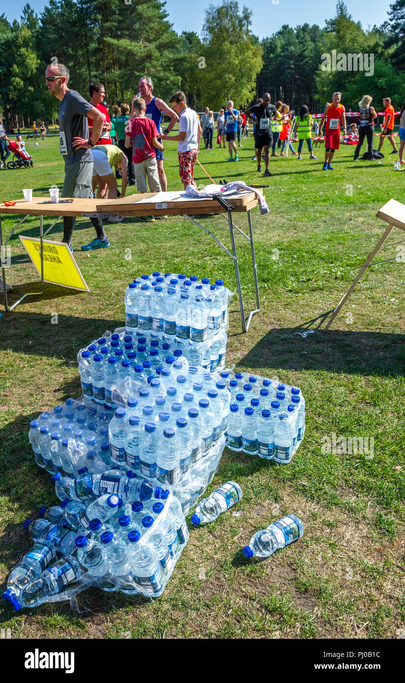 Bottiglia di plastica acqua essendo consegnati ai corridori al traguardo sul 2018 Sherwood Pines 10k. Foto Stock