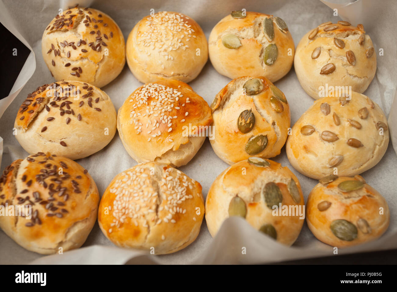 Freschi Fatti in casa panini hamburger con sesamo, zucca, lino, semi di girasole sul vassoio, concetto di burger e cibo fatto in casa. Mini challah Foto Stock