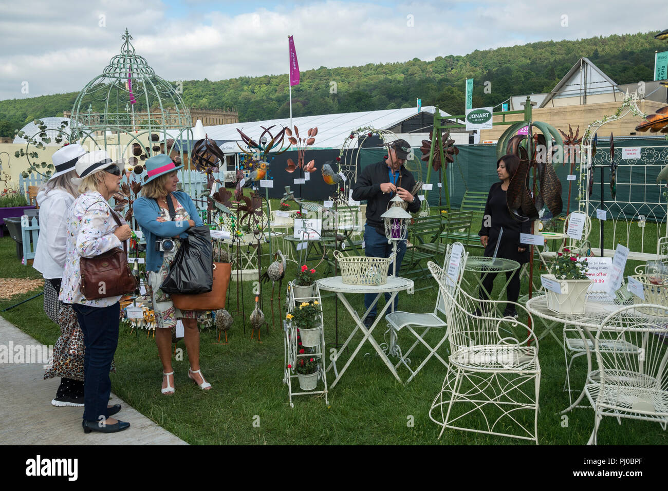 Le donne in piedi, guardando il display del giardino scultura & mobili in stallo a RHS Chatsworth Flower Show, la Chatsworth House, Derbyshire, England, Regno Unito Foto Stock