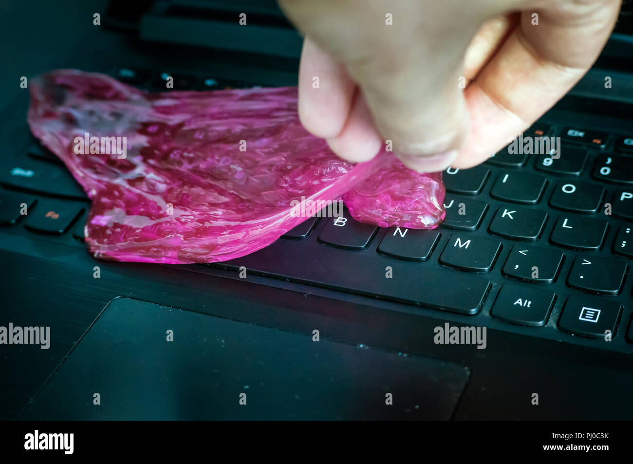 Red soft gel polvere pulizia in mano. La pulizia della tastiera del computer. Foto Stock