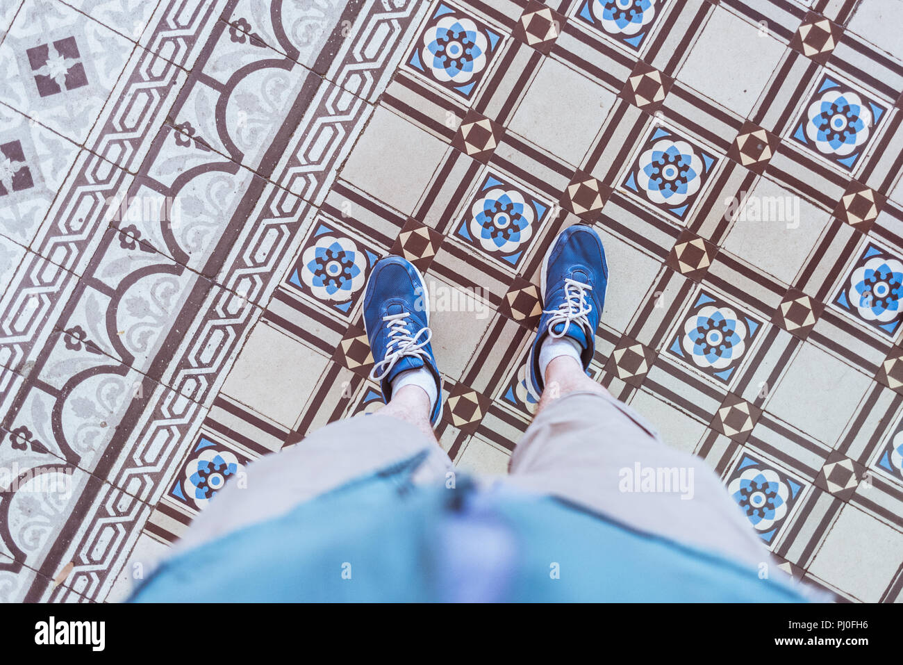 Piastrelle vecchie di edificio storico di Saigon Central Post Office (Città di Ho Chi Minh, Vietnam). Un selfie con sneakers blu sul pavimento piastrellato. Foto Stock