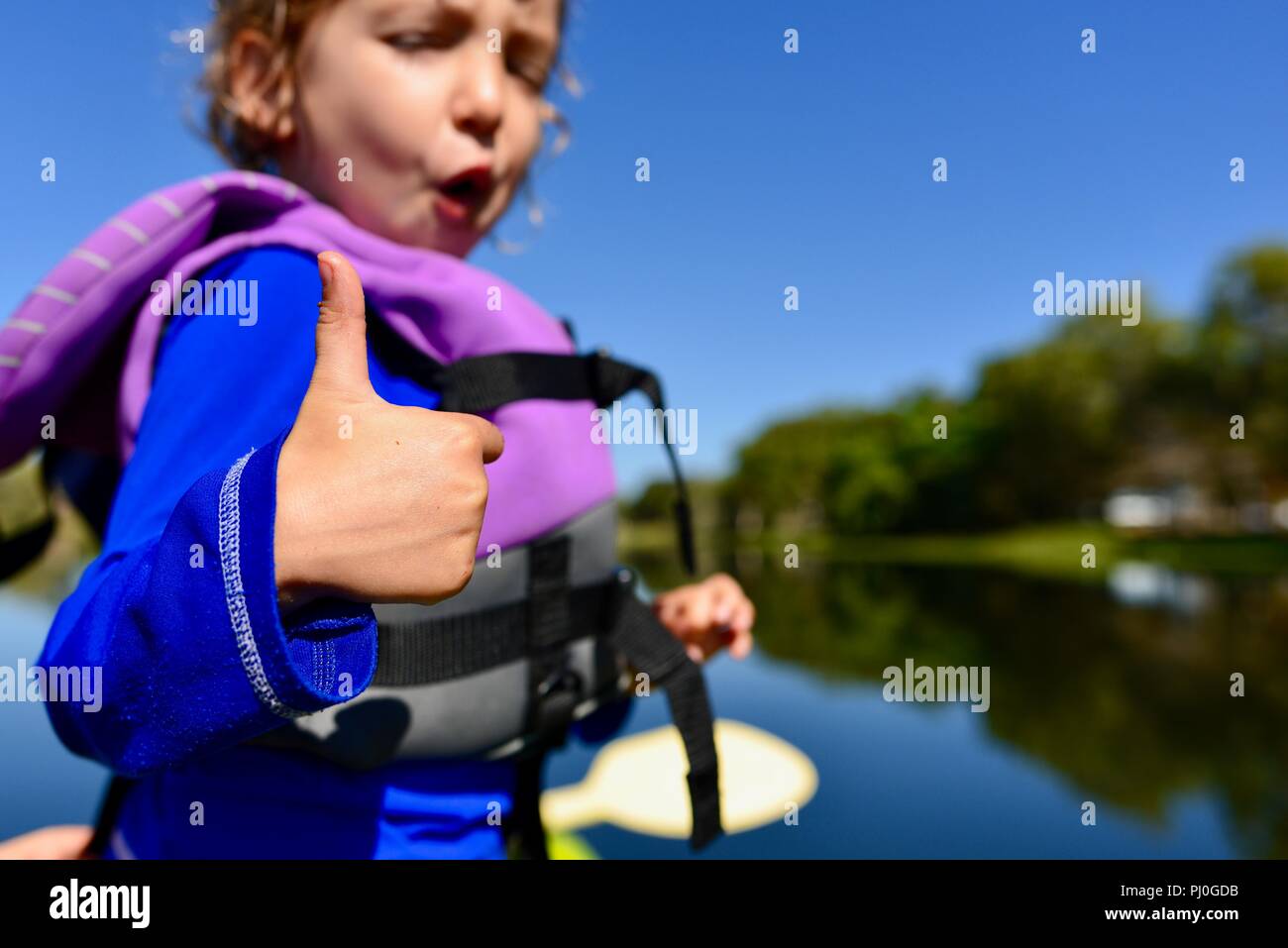 Bambino in un giubbotto di salvataggio dando un pollice in alto, del fiume Ross QLD, Australia Foto Stock