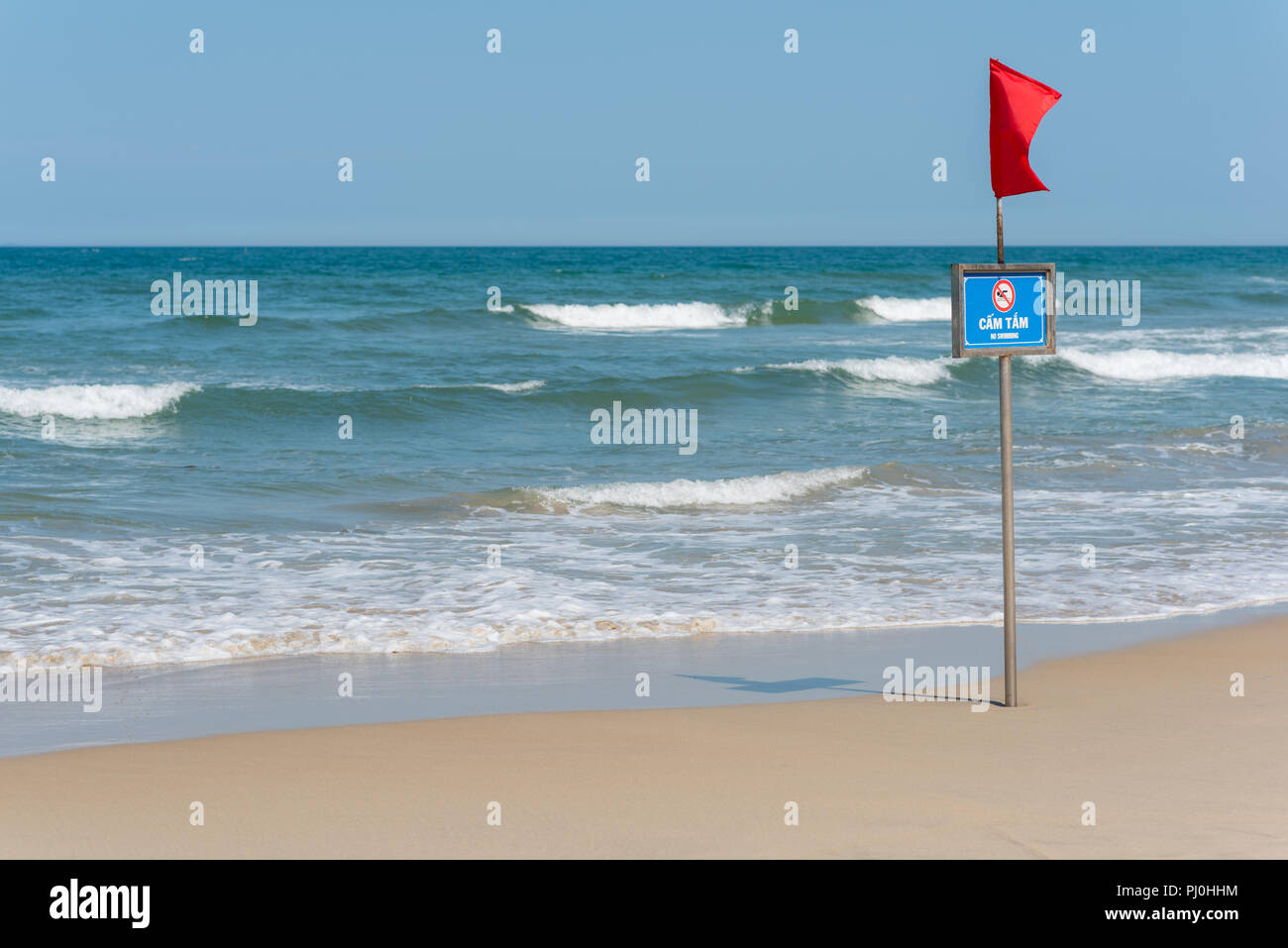 Bandiera rossa, il segno grafico e la scritta 'n' di nuoto in inglese e vietnamita sul mio Khe Beach (Da Nang, Vietnam) in maggio. Foto Stock