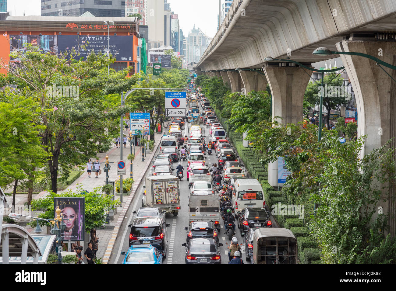 Inceppamento di traffico sulla Strada di Sukhumvit Road, vicino alla stazione BTS di Phrom Phong, Bangkok, Thailandia. BTS e le sue colonne di cemento sulla destra. Foto Stock