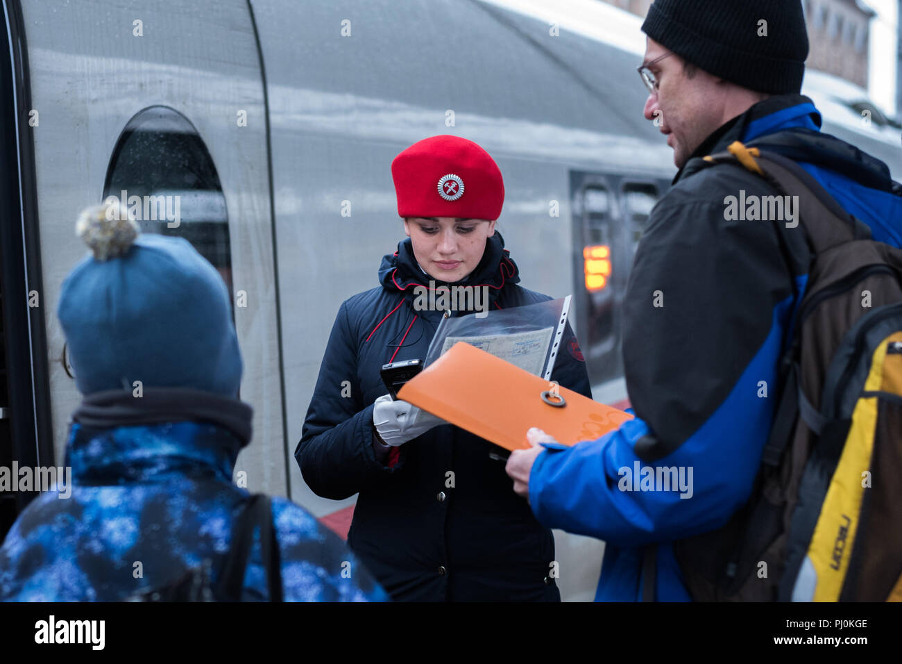 Treno russo conduttore in un berretto rosso di un Sapsan treno express controlli in un passeggero con un capretto utilizzando dispositivo elettronico a Moskovsky stazione ferroviaria Foto Stock