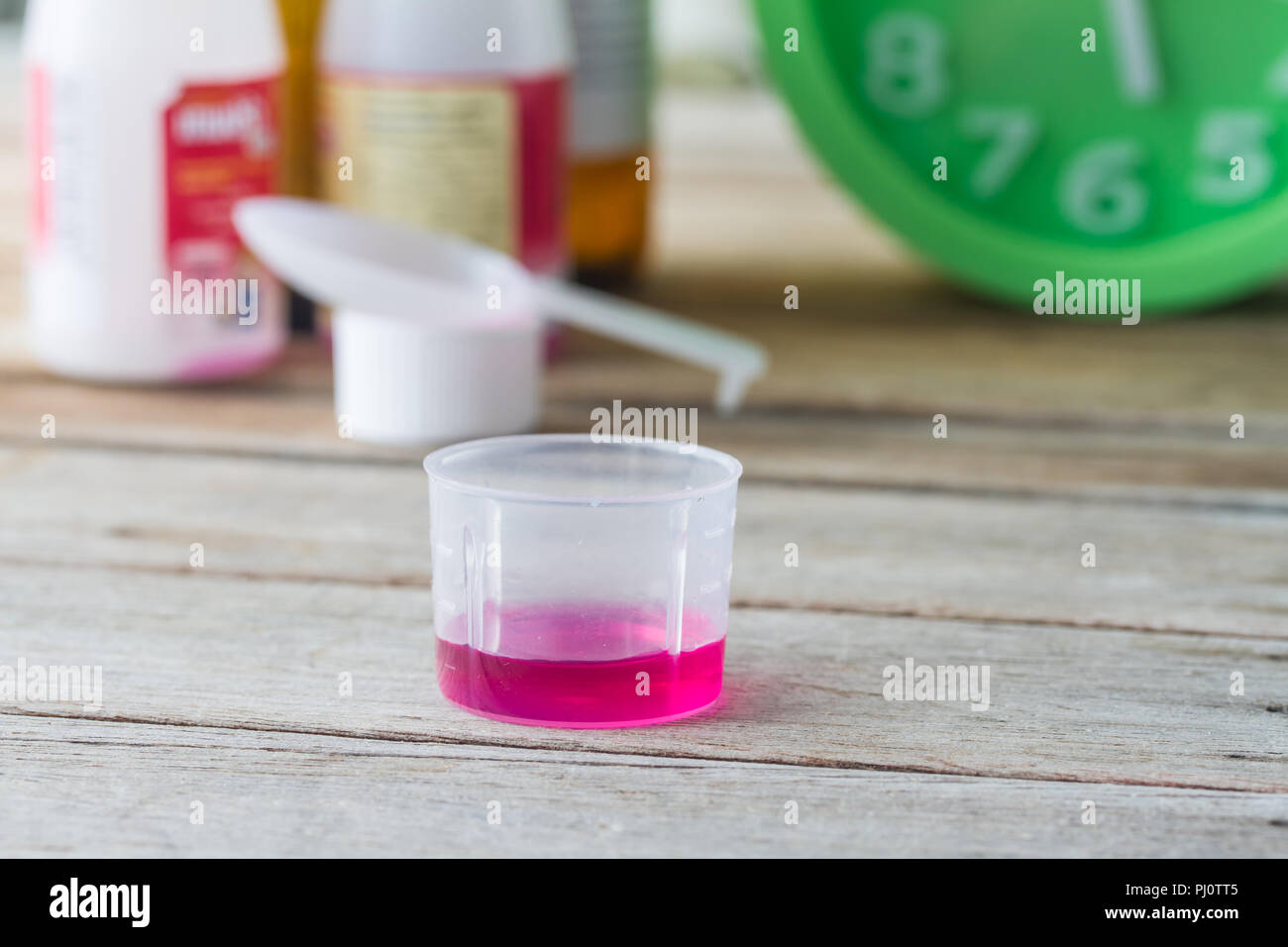 Medicina liquida in vetro di plastica su un tavolo di legno. Foto Stock