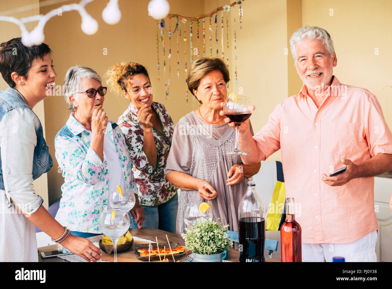 Felice il gruppo di allegro uomo caucasico e donne di età mista avente divertimento insieme mangiare e rinking per festeggiare. sorridere e ridere la gente godendo la fr Foto Stock