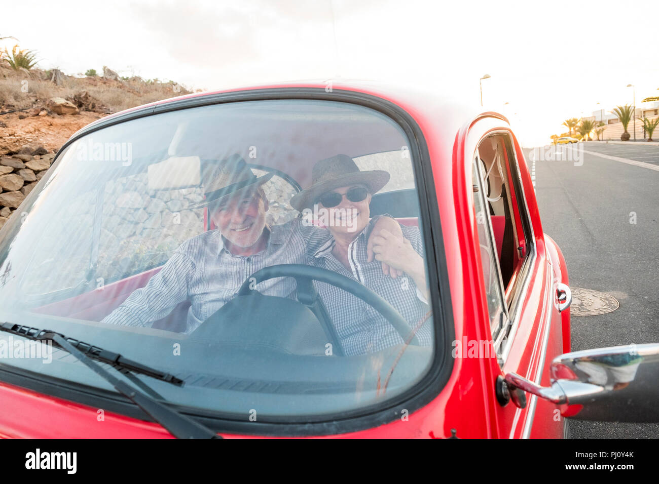 Nizza adulto giovane abbraccio e l'amore all'interno di un vecchio rosso vintage auto parcheggiate sulla strada. sorrisi e divertirsi viaggiando insieme. la felicità e lifestyle per ni Foto Stock