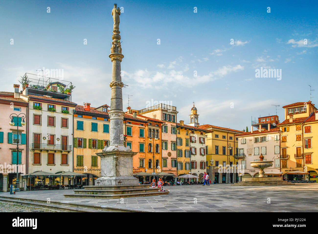 Piazza storica con statue e fontane e persone che si godono la Piazza San Giacomo di Udine Foto Stock