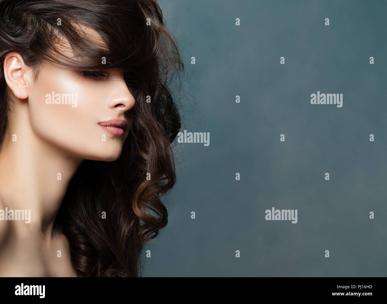Bellezza viso femminile, profilo. Modello femminile brunette con acconciature ondulate sullo sfondo con spazio di copia Foto Stock