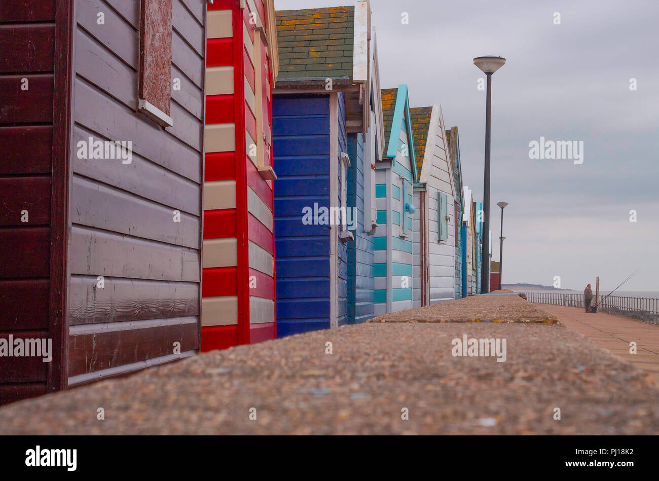 Il pescatore sul lungomare con spiaggia capanne in primo piano Foto Stock