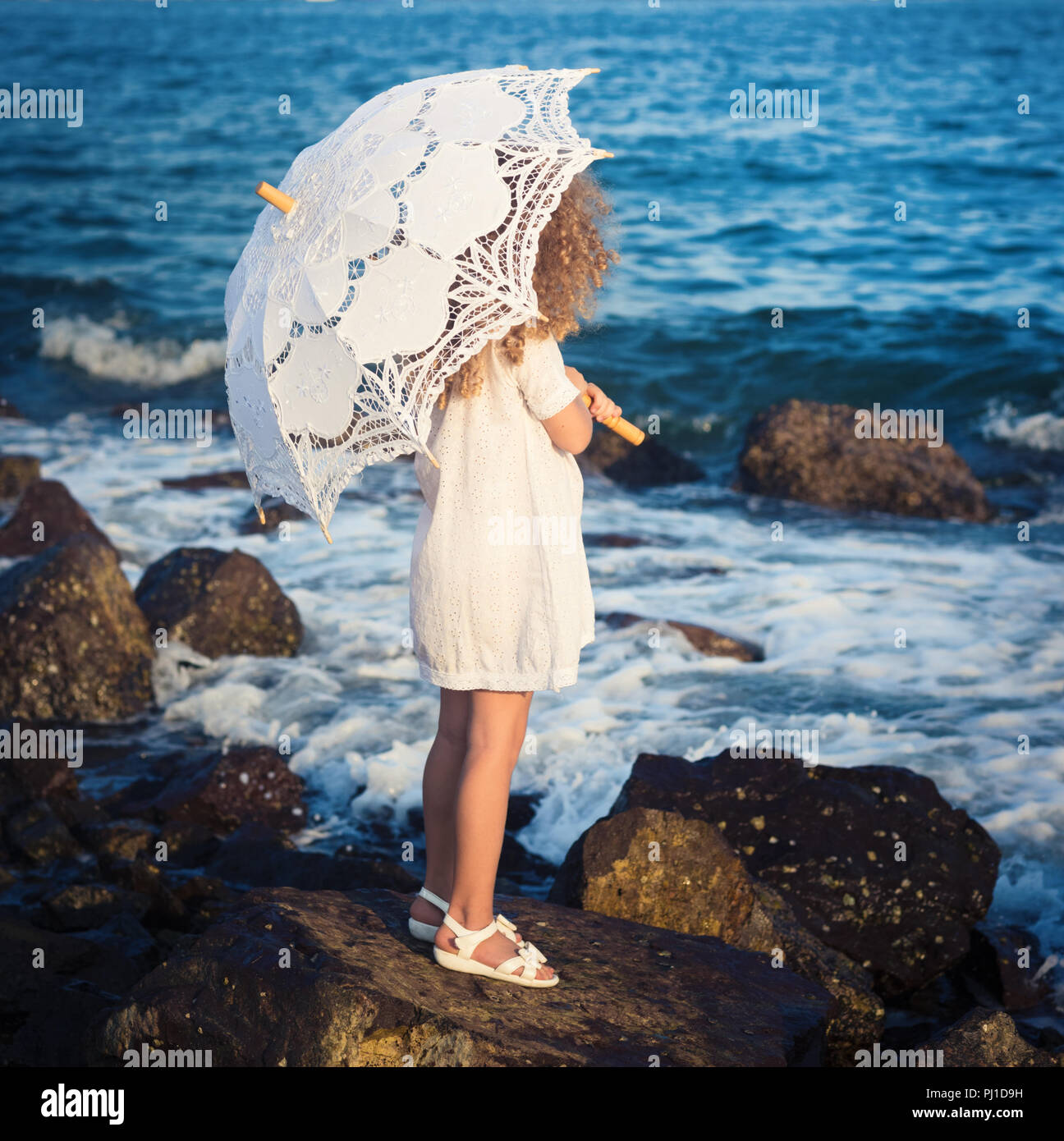 Bambina con ombrellone vicino al mare Foto Stock