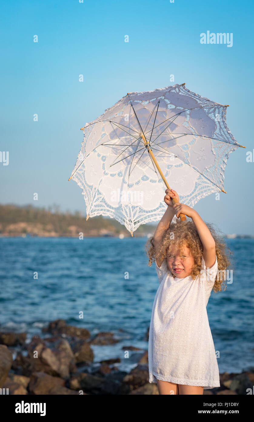 Bambina con ombrellone vicino al mare Foto Stock