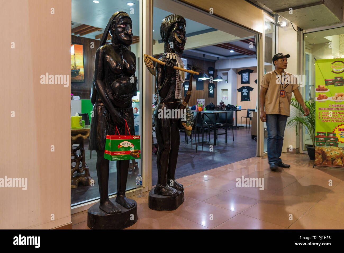 Nativo di sculture in legno di fronte a un piccolo cafe. Wamena, Papua occidentale, in Indonesia. Foto Stock