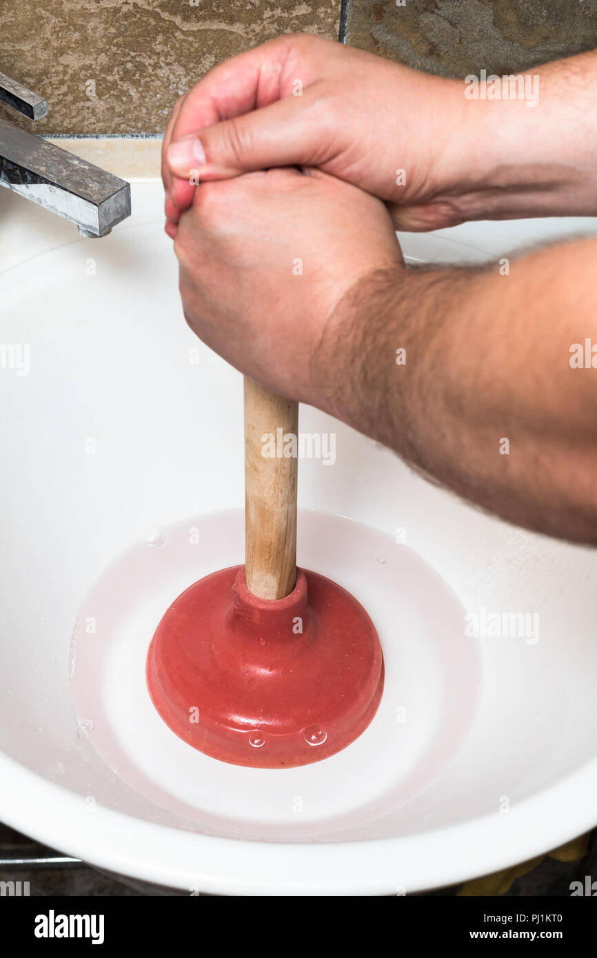 Plumber cancella blocco acqua nel lavello tubo dello stantuffo Foto Stock
