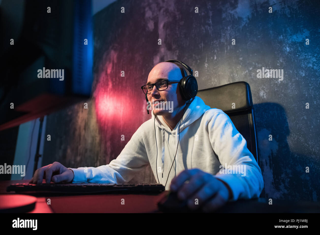 Tecnologia, giochi, intrattenimento, giochiamo e concetto di persone - happy giovane uomo in occhiali con auricolare Giocando e vincendo il gioco per computer a casa e lo streaming di gioco o procedura dettagliata video Foto Stock
