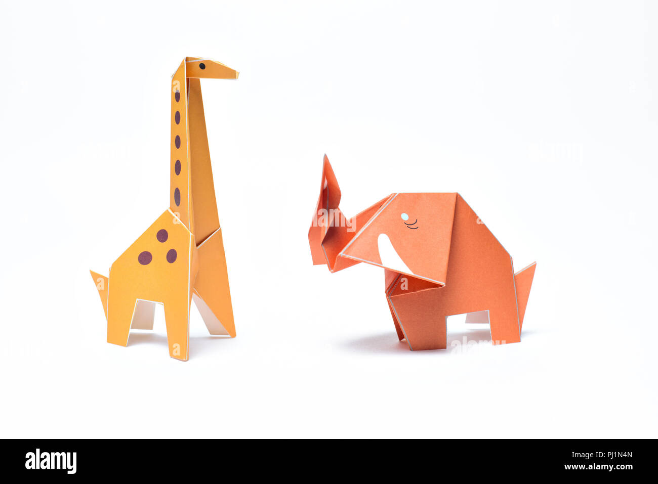 Un rosso elefante origami stand con un giallo giraffa origami su sfondo bianco Foto Stock