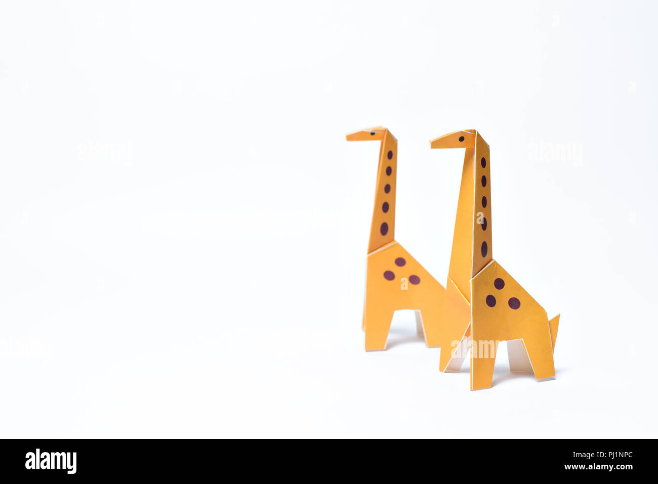Due origami giraffe su sfondo bianco con spazio di copia Foto Stock