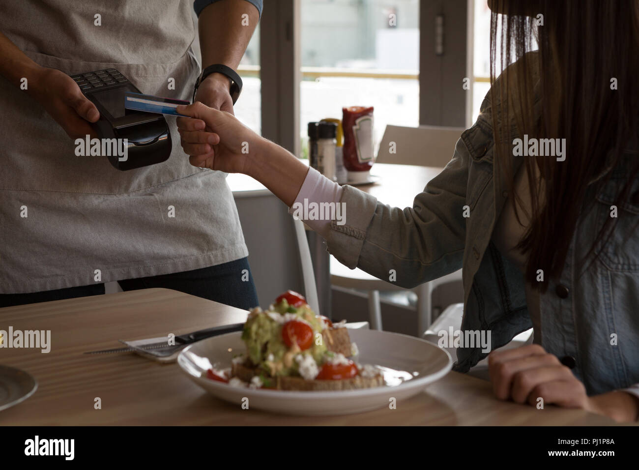 Donna pagando con la tecnologia NFC su carta di credito Foto Stock