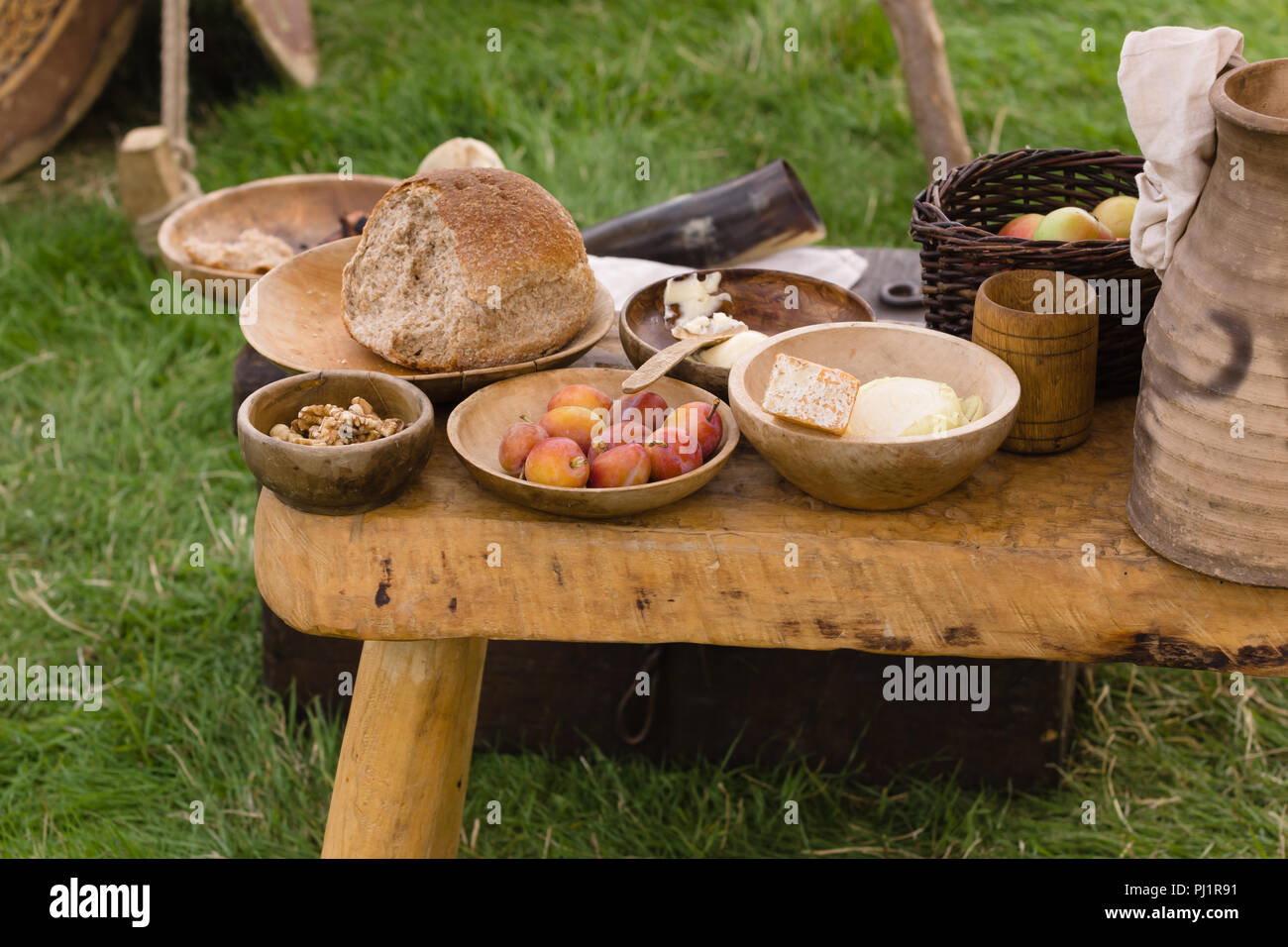 Selezione tipica medievale di cibo tra cui pane, burro, formaggio, frutta e noci servita in ciotole di legno o trenchers Foto Stock
