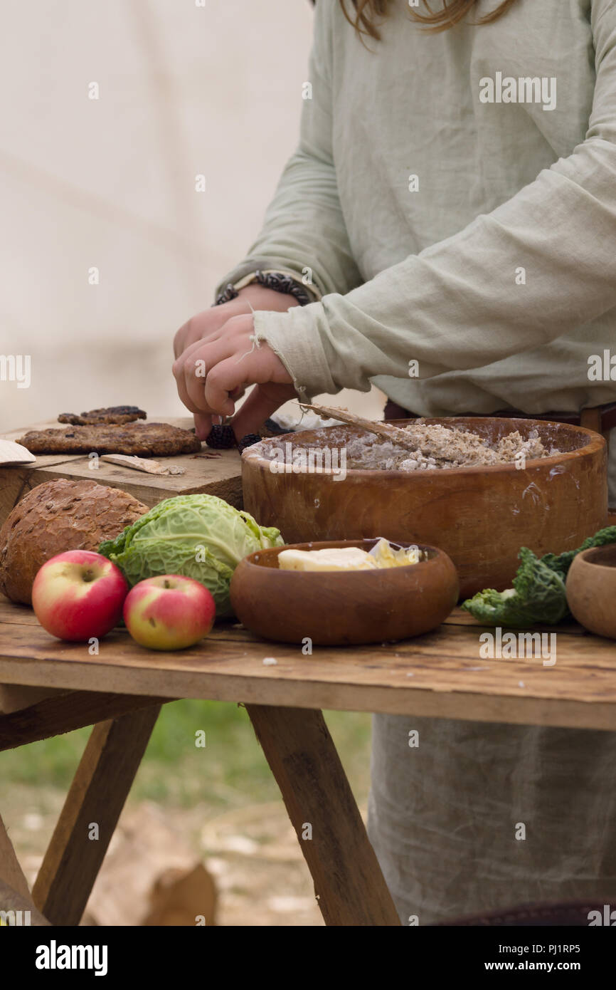 Medievale preparazione alimentare comprendente pane, burro, formaggi e frutta in ciotole di legno o trenchers Foto Stock