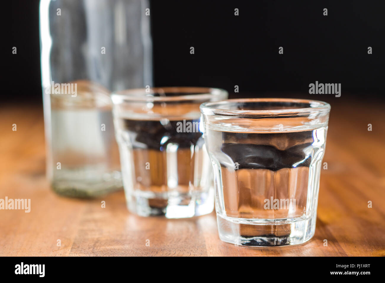 La vodka in colpo di vetro. Alcool trasparente su un tavolo di legno. Foto Stock