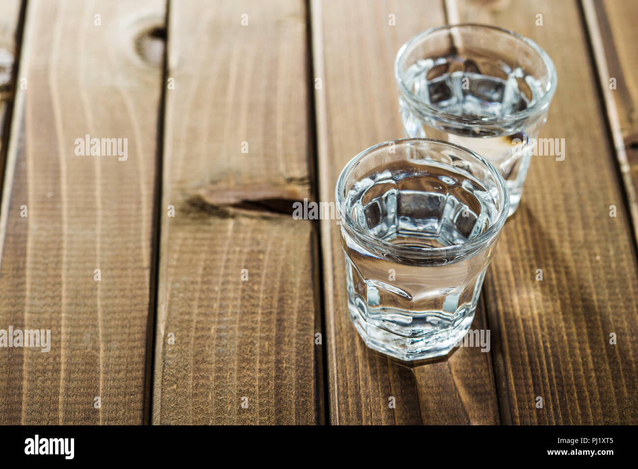 La vodka in colpo di vetro. Alcool trasparente su un tavolo di legno. Foto Stock