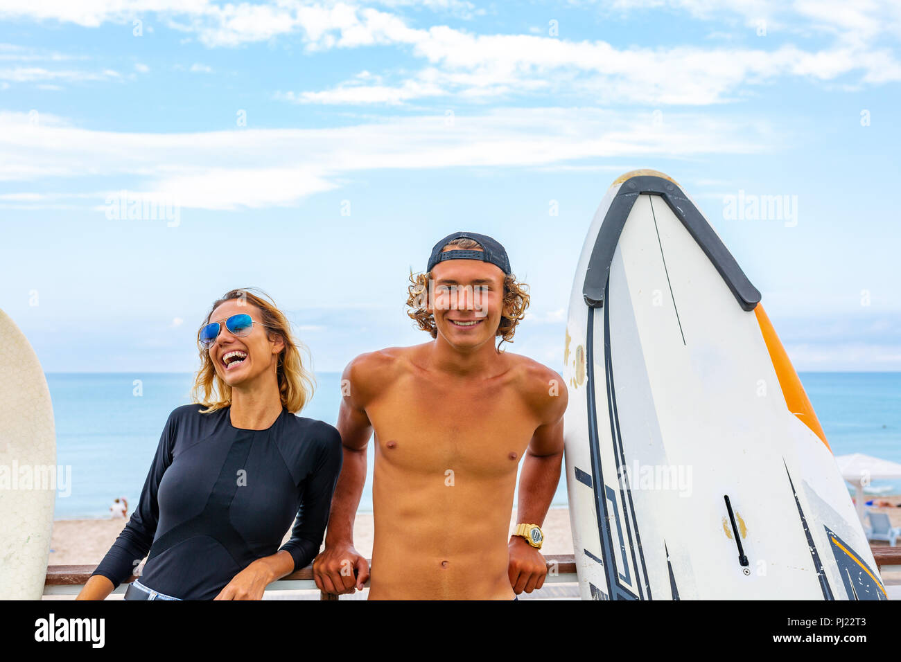 Sorridente giovani attiva giovane surfers rilassante sulla spiaggia dopo lo sport con la tavola da surf. Uno stile di vita sano. Extreme Sports Acquatici Foto Stock