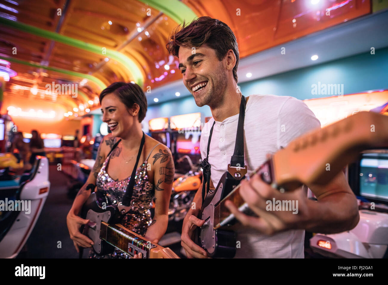 Matura in un gioco arcade la riproduzione musicale gioco chitarra. L uomo e la donna godendo la chitarra di gioco arcade in un salotto di gioco. Foto Stock