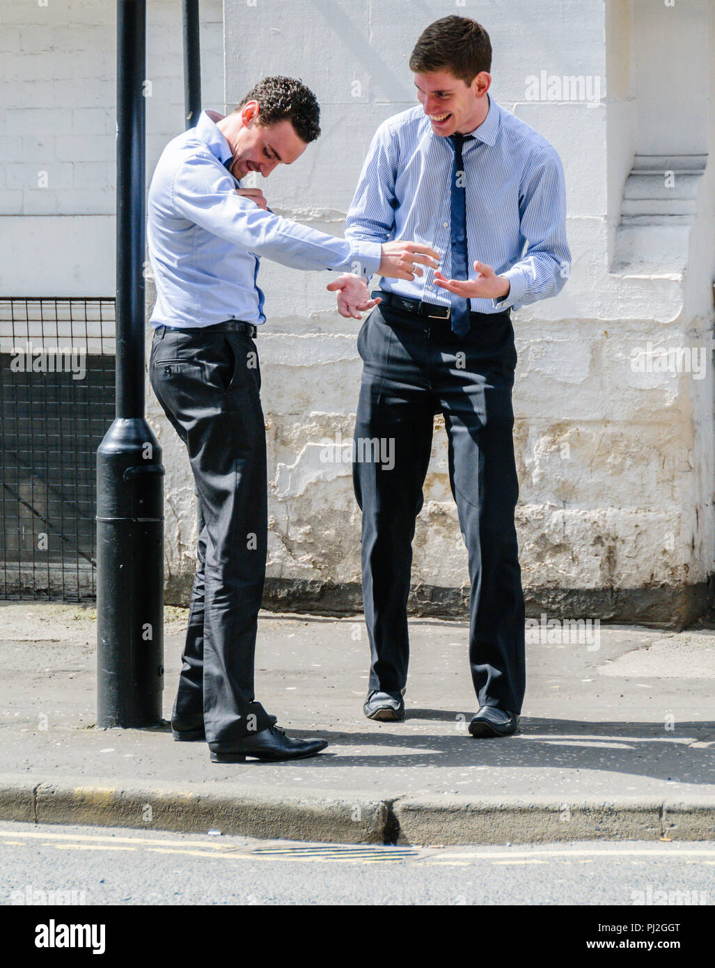 Due giovani uomini intelligenti di ridere gli uni con gli altri in una strada di Manchester durante una pausa dall'ufficio Foto Stock