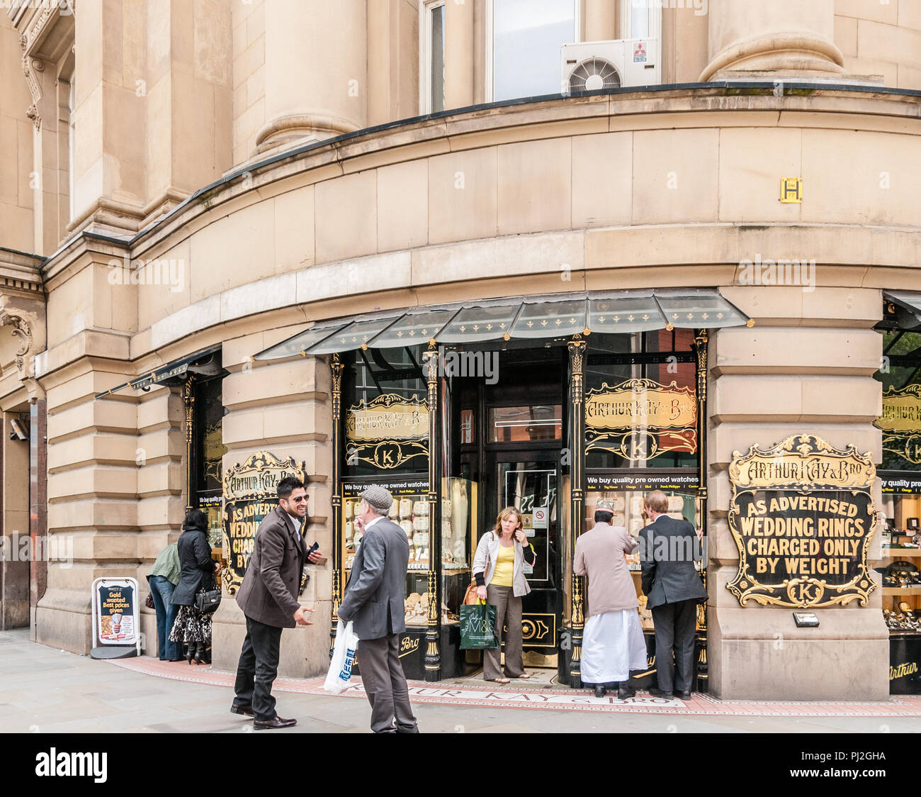 Due uomini di diverse età e le gare di conversazione e di salutare ciascuno di altri al di fuori di Arthur Kay gioiellerie in Manchester Foto Stock